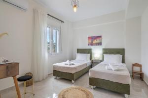 two beds in a room with white walls at Athena Home South Crete in Kapparianá