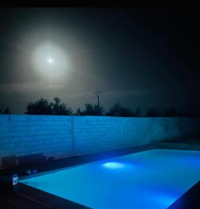 a swimming pool lit up at night with the moon at Lily Manzil in Ain Cheggag