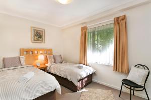 柏斯的住宿－Perth Short Stays，一间卧室设有两张床、一个窗口和椅子