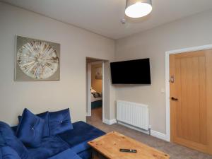 a living room with a blue couch and a flat screen tv at Apartment 2, Blackburn Heights in Bridlington