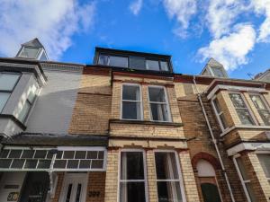 an old brick house with windows and a blue sky at Apartment 2, Blackburn Heights in Bridlington