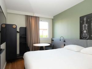 a bedroom with a bed and a table and a window at ibis Reims Tinqueux in Reims +23 photos