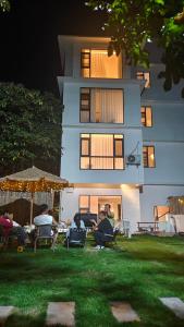 eine Gruppe von Menschen, die in Gartenstühlen vor einem Gebäude sitzen in der Unterkunft THAT MAY Hotel in Yangshuo