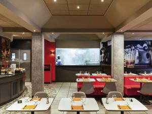 Un restaurante con mesas y sillas y una cocina. en ibis Douala, en Douala