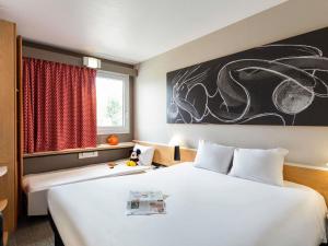 a hotel room with a large white bed and a window at ibis Bordeaux Pessac Route des Vins in Pessac