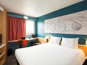 a hotel room with a large bed and a desk at ibis Bordeaux Pessac Route des Vins in Pessac +97 photos