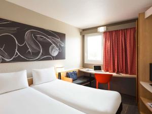 a bedroom with a bed and a desk with a laptop at ibis Bordeaux Pessac Route des Vins in Pessac