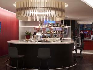 a bar in a restaurant with a large chandelier at Novotel Athens in Athens