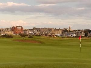 Ein Golfplatz mit einem Grün und einer Stadt im Hintergrund in der Unterkunft The Vintage - A Hidden Gem close to the Old Course in St Andrews