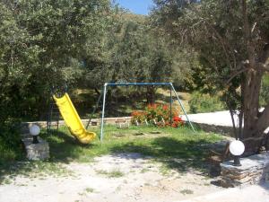 a playground with a yellow slide in a yard at Vassiliki Studios in Andros