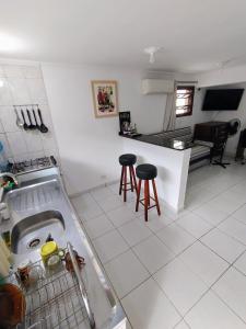 a kitchen with a sink and two bar stools at Espaço inteiro-Praia de Barequeçaba - São Sebastião -SP in São Sebastião