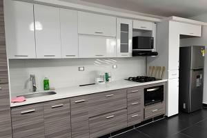 a kitchen with white cabinets and a black refrigerator at Palos altos house Poblado 6 min to Provenza in El Poblado
