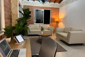 a living room with a couch and a table with a laptop at Palos altos house Poblado 6 min to Provenza in El Poblado