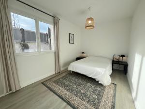 a white bedroom with a bed and a window at Maison moderne avec terrasse & parking in Clermont-Ferrand