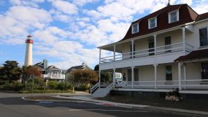 un phare se dresse au loin, derrière une maison dans l'établissement Renascence Cottage, à Cape May Point