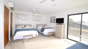 Cet appartement comprend une chambre avec deux lits, une télévision et un balcon. dans l'établissement Renascence Cottage, à Cape May Point