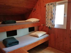 ein Zimmer mit zwei Etagenbetten in einer Kabine in der Unterkunft Les chalets au bord de l'étang de Malleteix in Champagnat