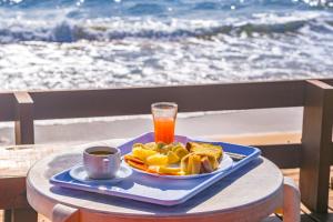 a plate of food and a glass of orange juice on a table at Mar a Vista by Concavus in Porto De Galinhas +32 photos