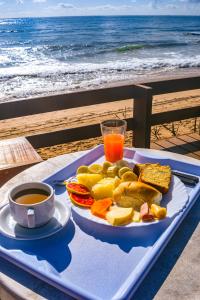 a tray of food and a cup of coffee on the beach at Mar a Vista by Concavus in Porto De Galinhas