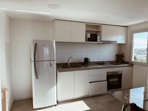 a white kitchen with a refrigerator and a window at Maju in Neuquén