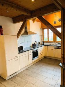 a large kitchen with white appliances and wooden ceilings at Haus Itten in Hondrich