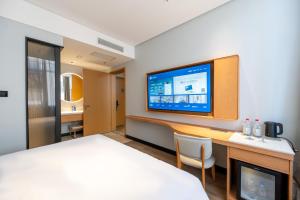 a hotel room with a bed and a desk with a tv at Hanting Hotel Beijing Garden Expo Park in Beijing