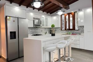 a kitchen with white cabinets and a counter with stools at Apt Palos Altos Poblado, a distancia caminando de restaurantes in Medellín +7 photos