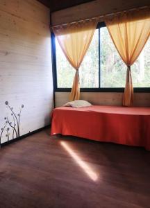 a bedroom with a red bed with a window at Cabaña Doña Teresa 2 Huéspedes in Tigre