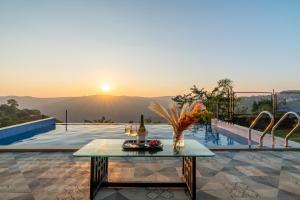 a table on a patio with a view of the sunset at Koko House - Infinity pool in Panchgani