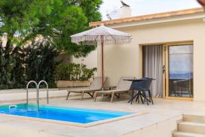 a pool with a table and chairs and an umbrella at Villa Aura Loutraki in Loutraki