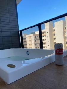 a white bath tub in a room with a large window at Flats Tramonto - By EasyHost in João Pessoa