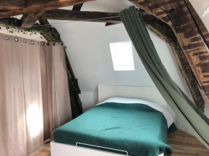 a bedroom with a green bed in a attic at Le Godefroy de Bouillon in Boulogne-sur-Mer