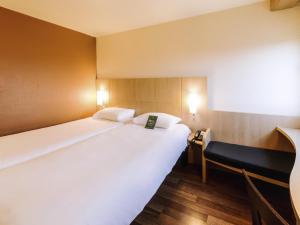 a hotel room with a large white bed and a desk at ibis Avignon Centre Gare in Avignon