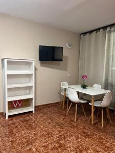 una sala da pranzo con tavolo, sedie e TV di Beautiful Apartment Hercules a Costa Del Silencio