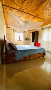 a large bed in a room with a wooden ceiling at Minerva Apart in Ranomafana