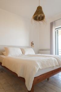 een witte slaapkamer met een groot bed met witte lakens bij Panorama SeaView House in Marinha Grande