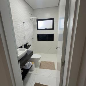 a white bathroom with a sink and a toilet at Recanto dos Sonhos Ninho Verde 2 in Pardinho