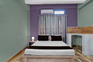 een slaapkamer met een groot bed met paarse muren bij Hotel O Junaki Inn in Guwahati