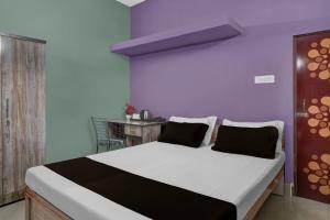 een slaapkamer met een groot bed met een paarse muur bij Hotel O Junaki Inn in Guwahati