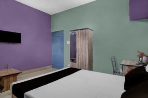 een slaapkamer met een bed en een tv aan de muur bij Hotel O Junaki Inn in Guwahati