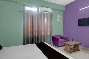 een slaapkamer met een bed en een paarse stoel bij Hotel O Junaki Inn in Guwahati +21 foto's