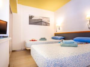 Una habitación con dos camas con almohadas azules y un televisor en Charming apartment with an excellent location, en Arona