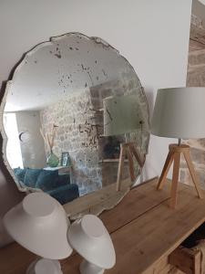 a mirror on a table with a couch and a lamp at La belle cachée in Sévérac d' Aveyron