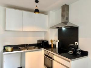 a kitchen with white cabinets and a black counter top at Le Perché in Melun
