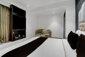 a bedroom with a large white bed and a television at Hotel O elvilla in New Delhi