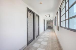 a hallway with white walls and windows and a tile floor at Hotel O Vatva Railway Station Formerly Anmol Palace in Ahmedabad