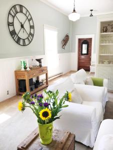 a living room with a white couch and a clock on the wall at Picturesque School House Retreat in Meaford
