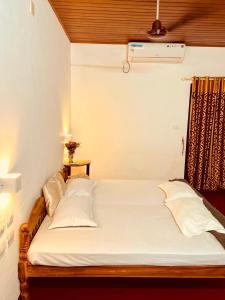 马拉利库兰Marari La Vista的房间里有一张铺着白色床单和枕头的床 更多25张照片