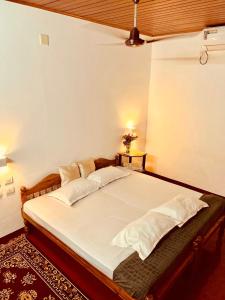 马拉利库兰Marari La Vista的房间里有一张铺着白色床单和枕头的床