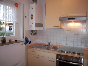 une cuisine avec des armoires blanches, un évier et une fenêtre dans l'établissement Ferienhaus Barbara am Meer, à Horumersiel 6 autres photos